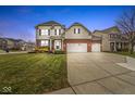 Two-story home with a three-car garage, neat landscaping, and a brick facade at 7648 Three Arch Overlook, Noblesville, IN 46062