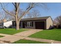 Gray house with black garage door, freshly cut lawn and a mature tree in front at 2707 Aurie Dr, Indianapolis, IN 46219