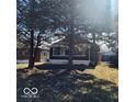 Cute bungalow with a covered porch, partially visible from behind trees at 3949 English Ave, Indianapolis, IN 46201