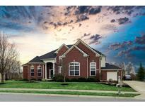 Brick two-story home with a three-car garage and manicured lawn under a dramatic sky at 2569 Dawn Ridge Dr, Carmel, IN 46074