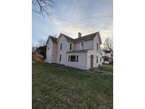 Two-story house with light beige siding, a large yard, and mature trees at 213 E Broadway St, Alexandria, IN 46001