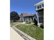 Charming bungalow with a blue exterior, well-manicured lawn, and mature tree at 602 Parkway Ave, Indianapolis, IN 46203