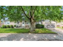 Stone house with a large tree and two-car garage at 11445 N School St, Fishers, IN 46038
