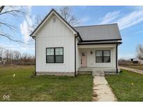 Charming white farmhouse exterior with pink door and gray metal roof at 706 S Main St, Whitestown, IN 46075