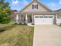 Beige house with stone accents, a two-car garage, and a well-maintained lawn at 6024 Rockdell Dr, Indianapolis, IN 46237