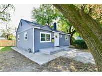 Charming gray house with a well-manicured lawn and mature trees at 2035 N Tibbs Ave, Indianapolis, IN 46222