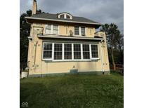 Two-story house with yellow stucco exterior and sunroom at 548 Central N Ct, Indianapolis, IN 46205