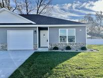 Gray ranch house with white garage door, landscaping, and a brick accent at 1441 Coen Ct, Columbus, IN 47201