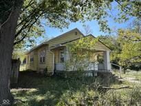 Yellow bungalow with front porch and mature trees at 3221 E 38Th St, Indianapolis, IN 46218