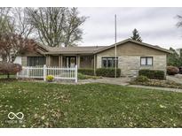 Ranch home with stone accents, landscaping, and a white picket fence at 700 Orchard Ln, Greenwood, IN 46142