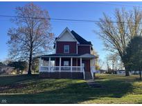 Two-story red house with white trim, a porch, and a well-maintained lawn at 503 E Clyde St, Frankton, IN 46044