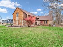 Two-story house with wood siding and stone accents, situated on a spacious lawn at 11510 E 10Th St, Indianapolis, IN 46229