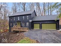 Two-story dark exterior home with green garage doors, deck, and basketball hoop at 10455 Courageous Dr, Indianapolis, IN 46236
