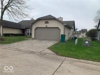 Beige one car garage with driveway and grassy yard at 4112 Eagle Cove E Dr, Indianapolis, IN 46254