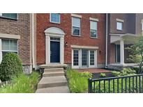 Brick front exterior of townhome with steps leading to the entrance and a small patio area at 9558 Oakley Dr, Indianapolis, IN 46260
