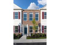 Brick front elevation of charming townhome with dark shutters and a small front yard at 718 Kinzer Dr, Carmel, IN 46032