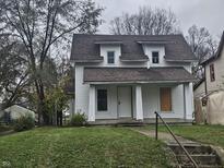 White two-story house with brown roof, steps, and small lawn at 2702 Boulevard Pl, Indianapolis, IN 46208