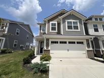 Two-story townhome with gray siding, white garage door, and landscaping at 9592 Beckett St, Avon, IN 46123