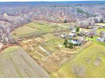 Aerial view showing a large property with farmlands, a pond, and multiple buildings at 7021 Bellsville Pike, Columbus, IN 47201