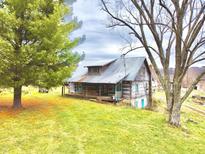 Rustic log cabin with a covered porch and metal roof, nestled in a green lawn at 7021 Bellsville Pike, Columbus, IN 47201