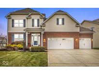 Two-story brick and beige home with a three-car garage and well-manicured lawn at 7648 Three Arch Overlook, Noblesville, IN 46062