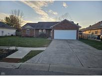 Brick ranch home with attached garage and landscaped lawn at 14 Watson Dr, Trafalgar, IN 46181