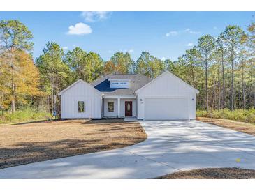 White farmhouse exterior with gray accents, a two-car garage, and a landscaped lawn at 6174 Highway 66, Loris, SC 29569