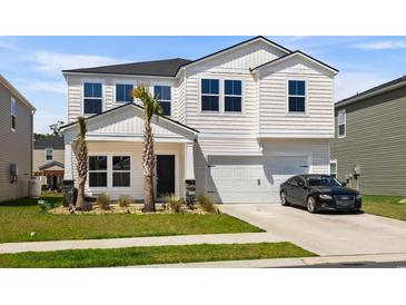 Two-story house with a white exterior, two-car garage, and palm trees at 1087 Saltgrass Way, Myrtle Beach, SC 29588