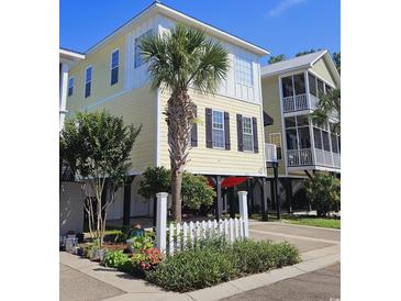 Two-story beach house with a yellow exterior, white trim, and black shutters at 5226 Highway 17 Business, Murrells Inlet, SC 29576