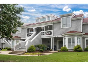 Gray two-story townhome with a red roof, stairs, and landscaping at 4396 Baldwin Ave. # 109, Little River, SC 29566