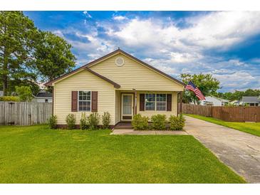 Cute yellow house with brown accents, landscaped lawn, and American flag at 8089 Bark Ct., Murrells Inlet, SC 29576