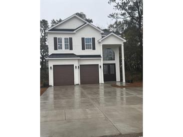 Two-story house with white siding, brown garage doors, and a landscaped front yard at 2247 Sand Dunes Dr., Myrtle Beach, SC 29577