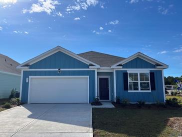 Charming blue house with white garage door and landscaped lawn at 573 Duvall St., Longs, SC 29568