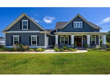 Charming farmhouse exterior boasts a gray facade, stone accents, and a welcoming front porch at 250 Samuel Rd., Loris, SC 29569