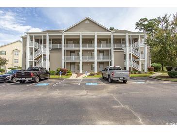 Two-story condo building with ample parking and tree-lined surroundings at 5810 Longwood Dr. # 14-304, Murrells Inlet, SC 29576