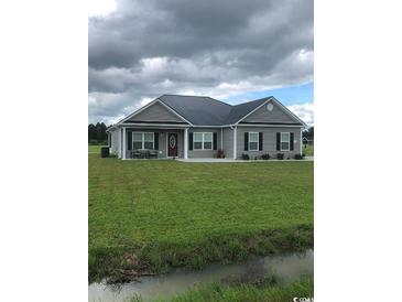 One story home with gray siding, dark metal roof, and large yard at Lot#8 Justice Loop, Loris, SC 29569