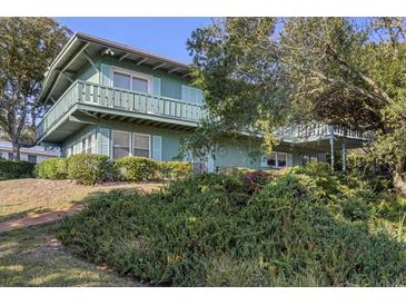 Two-story house with a balcony, surrounded by lush greenery at 1000 Strand Ave., North Myrtle Beach, SC 29582