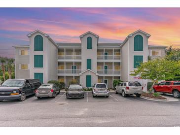 Condo building exterior with parking lot and cars at 1100 Commons Blvd. # 107, Myrtle Beach, SC 29572