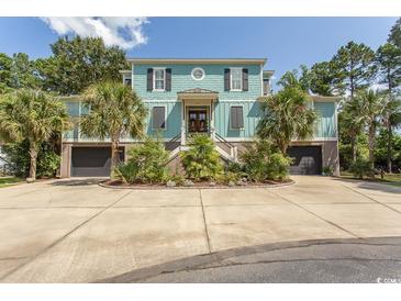 Attractive two-story home with a light teal exterior, lush landscaping, and a circular driveway at 119 Cockle Shell Ct., Pawleys Island, SC 29585