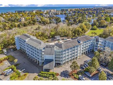 Aerial view of a coastal community with a large building and ocean in the distance at 14290 Ocean Hwy. # 202, Pawleys Island, SC 29585