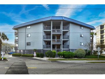 Gray building with blue roof, multiple balconies, and landscaping at 6000 N Ocean Blvd. # 304, North Myrtle Beach, SC 29582