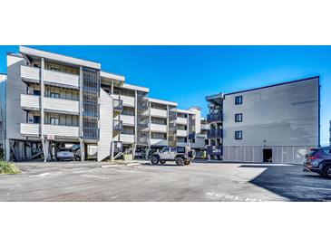 Exterior view of a beach condo building with parking and cars at 814 N Waccamaw Dr. # 311, Garden City Beach, SC 29576