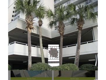 One Ocean Place building exterior with palm trees and signage at 1990 N Waccamaw Dr. # 1209, Garden City Beach, SC 29576