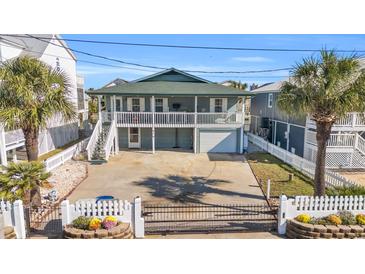 Two-story home with a green roof, white fence, and a driveway at 310 34Th Ave. N, North Myrtle Beach, SC 29582