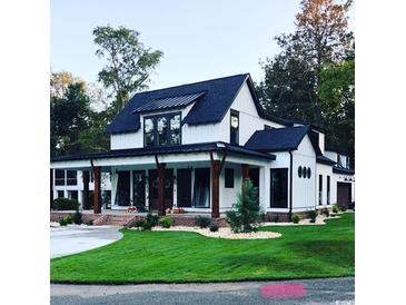 Two-story farmhouse with a wraparound porch, brick accents, and a landscaped lawn at 828 Channel Cat Cove, Murrells Inlet, SC 29576