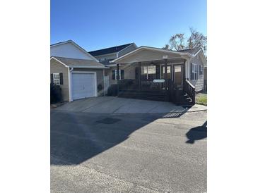 Tan house with a porch, dark brown steps, and attached garage at 6001-1774 S Kings Hwy., Myrtle Beach, SC 29575