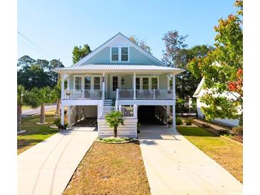 Two-story light blue house with a metal roof, front porch, and driveway at 314 Hollywood Dr. S, Surfside Beach, SC 29575