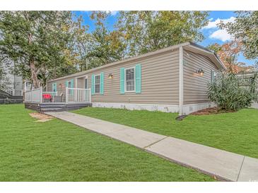 Tan mobile home with teal accents, deck, and landscaped lawn at 6001-Mh81 S Kings Hwy., Myrtle Beach, SC 29575