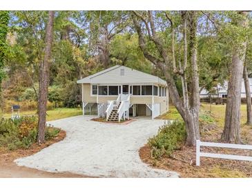 Charming raised cottage with screened porch and gravel driveway at 137 Whipporwill Dr, Pawleys Island, SC 29585