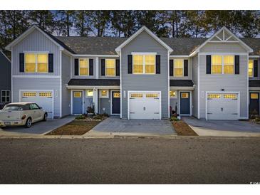Three-unit townhome building, gray siding, two-car garages, and well-manicured landscaping at 608 Montenegro Way # E, Myrtle Beach, SC 29579